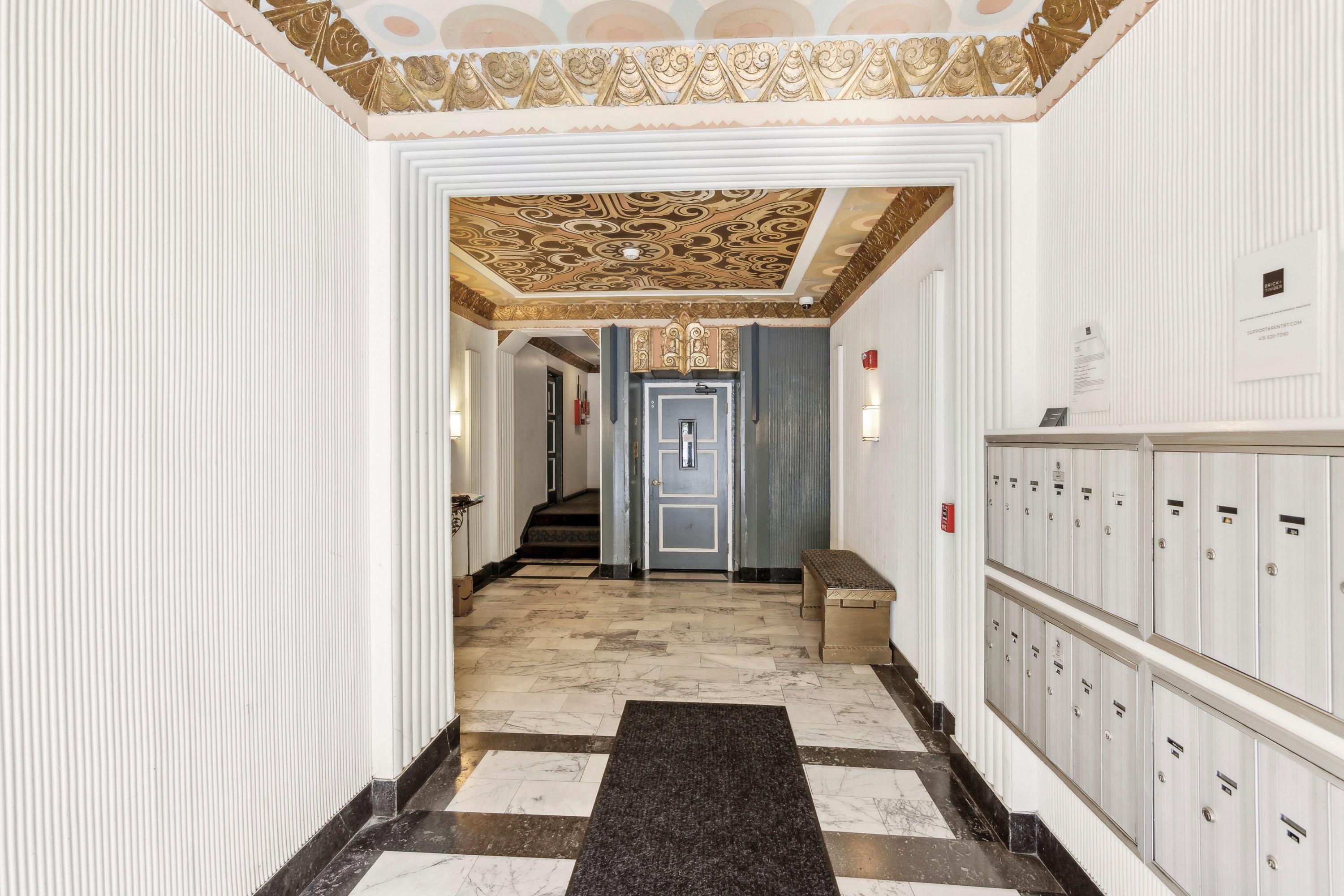 A hallway with a bench and a door at the end.